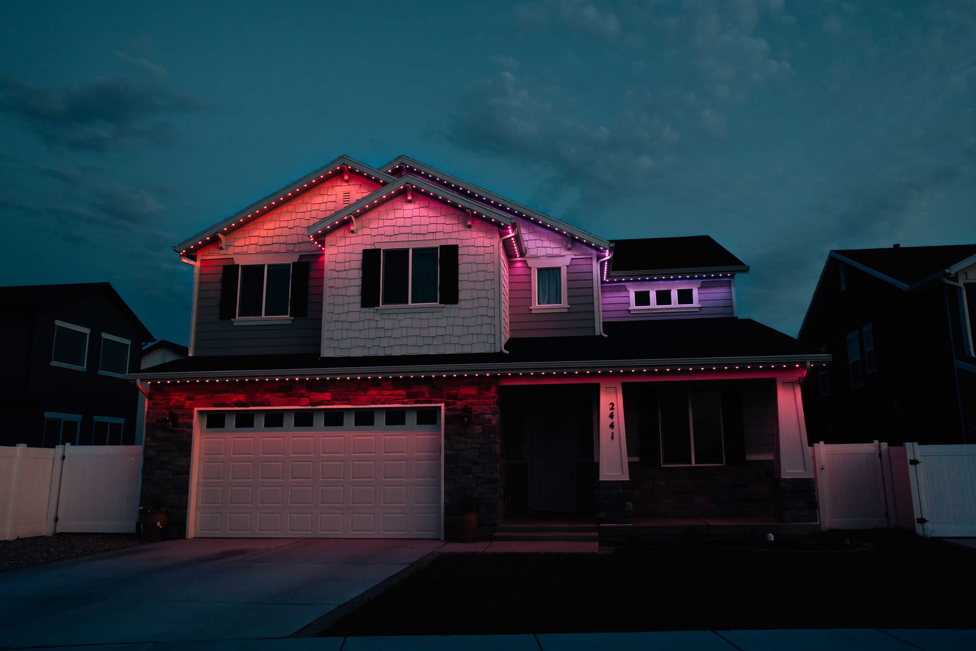 Two-story craftsman home lit in a gradient of pink and purple at dusk