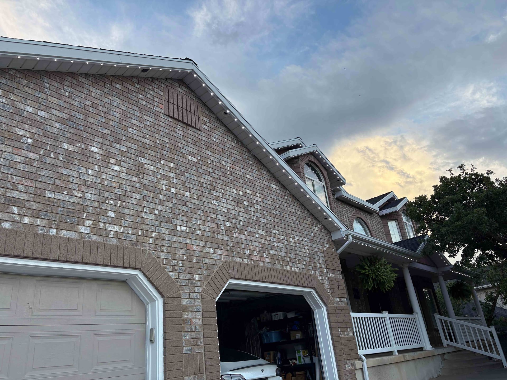 Close-up of brick eaves with clean white permanent lighting at dusk
