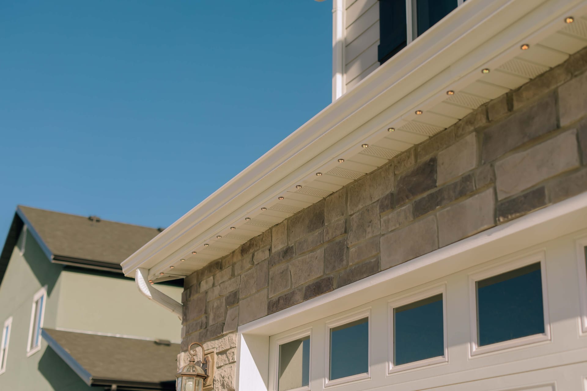 Discreet recessed permanent lighting installed along a home's white soffit
